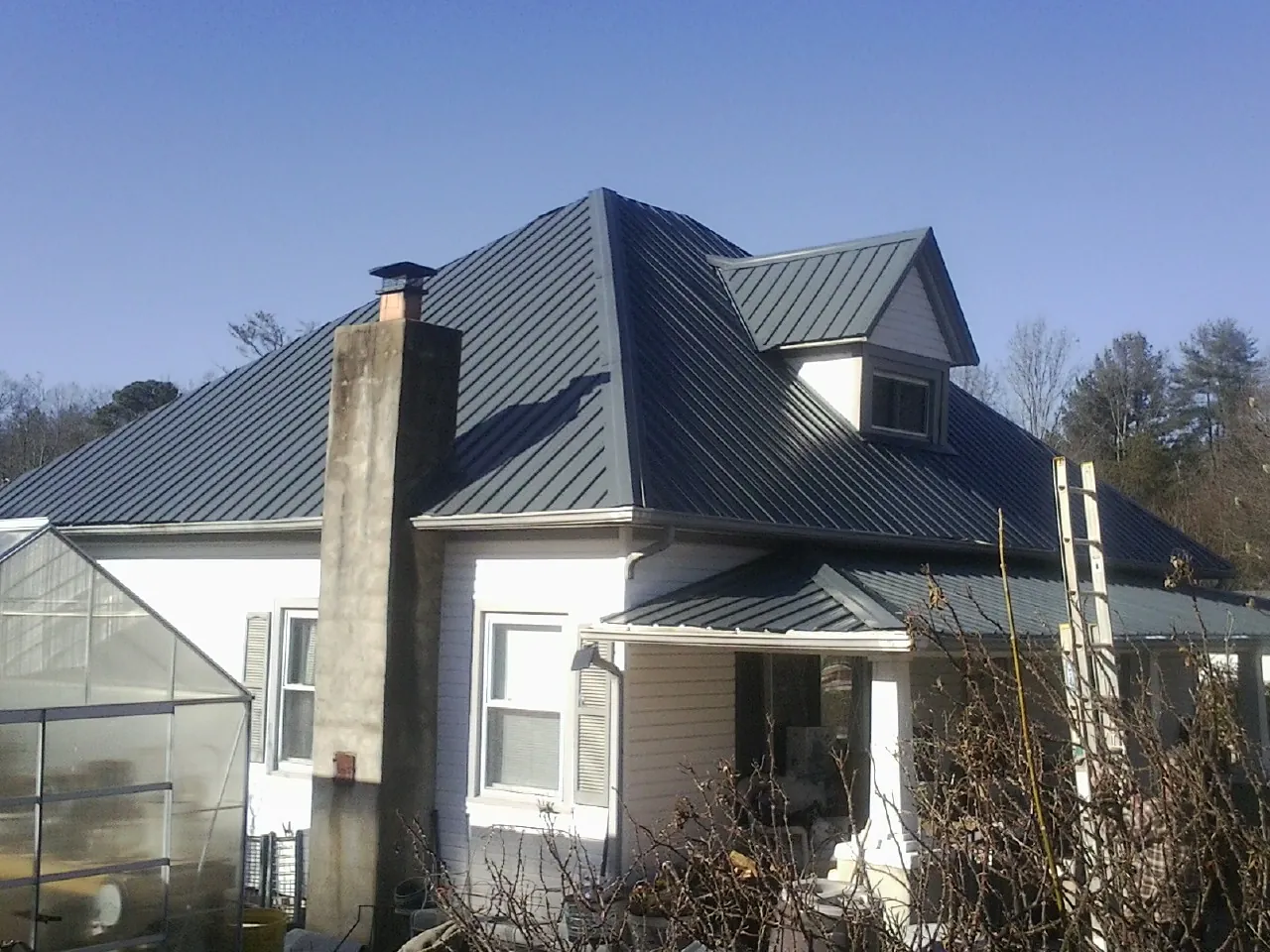 Dark blue standing seam metal roof on a white farmhouse with dormer — Slate & Tile Roof Repair by Roofing Brothers in Belleville