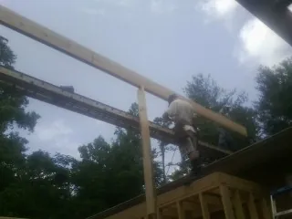 Carpenter setting a ridge beam over a new addition frame — Ice Dam Removal by Roofing Brothers in Belleville